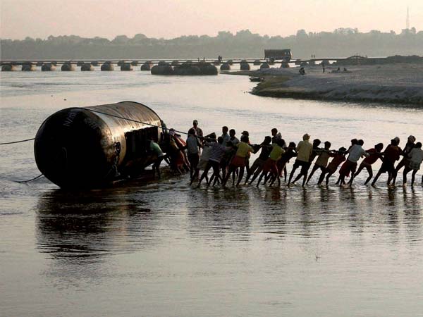 Labourers work to construct a temporary pontoon bridge