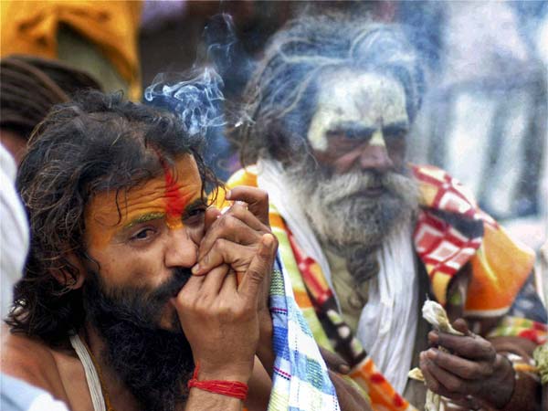 Naga sadhu smokes a chillum on a cold day