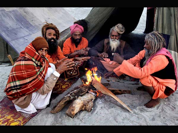 Juna Akhada Naga Sadhus warming themseleves around a fire