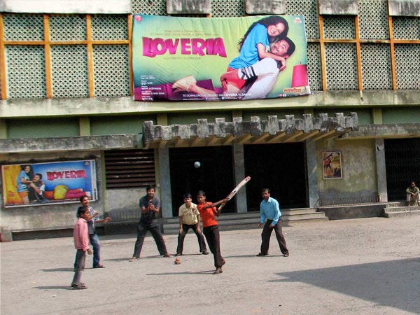 Children Play cricket in front of a closed cinema hall