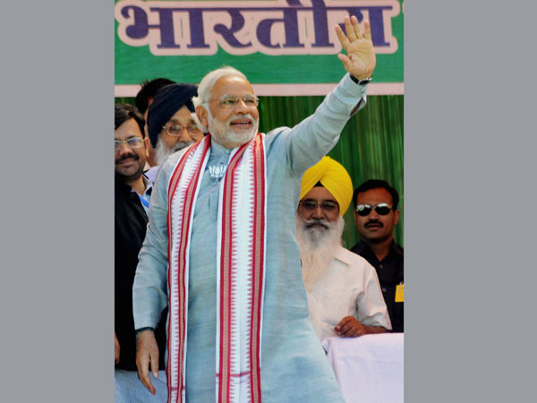 Narendra Modi waves at supporters during an election rally