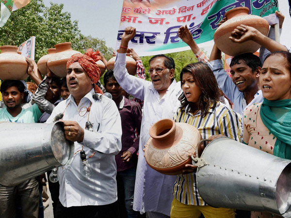 Protesters carry pitchers and buckets during a protest
