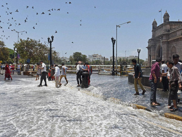 People walk cautiously at a road inundated after a high tide