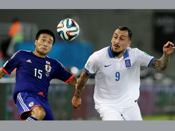 Japan's Yasuyuki Konno, left, holds on to Greece's Kostas Mitroglou