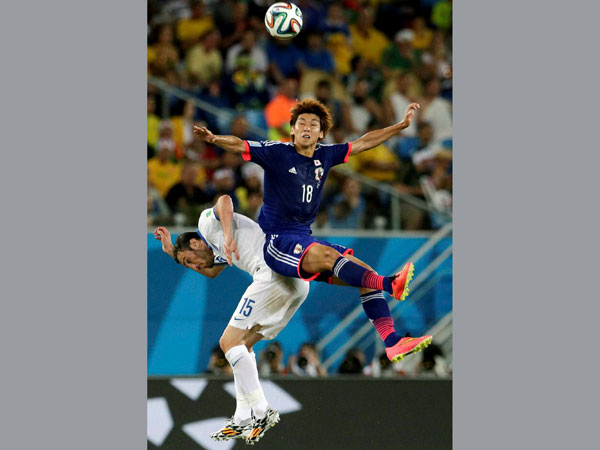Japan's Yuya Osako, right, leaps over Greece's Vasilis