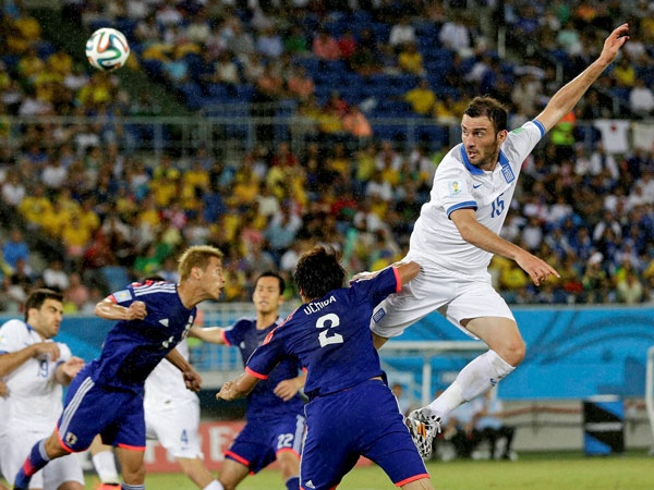Greece's Vasilis Torosidis, right, rises high to win a header