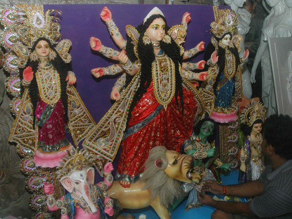 Subol Paul, an artist gives finishing touches to an idol of goddess Durga