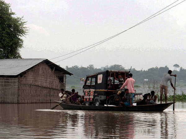 Villagers carry an auto rickshaw on a boat to safer areas