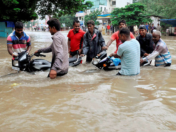 People pushing motorcycles stuck in a flooded locality