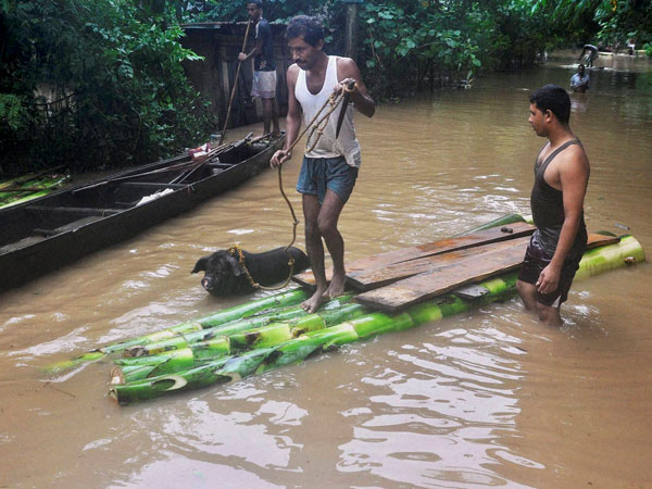 Villagers use a makeshift banana plantain raft to move across their flooded village