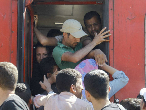 Migrants push each other trying to secure a place in train