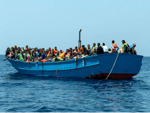 Migrants stand on a wooden boat in the Mediterranean Sea