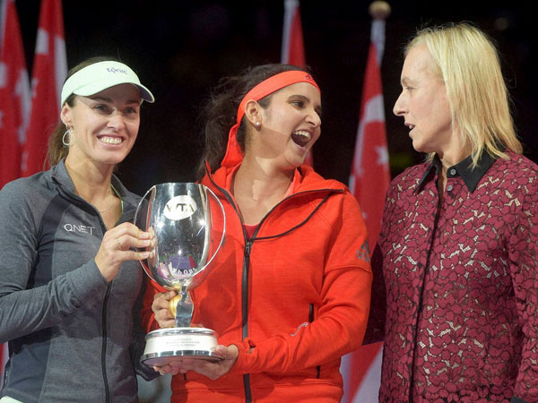 Sania Mirza of India, center, laughs and speaks to retired tennis player Martina Navratilova as she and her partner, Martina Hingis of Switzerland, left, are presented with their trophy after winning the doubles event at the WTA tennis finals in Singapore. Sania Mirza of India, center, laughs and speaks to retired tennis player Martina Navratilova as she and her partner, Martina Hingis of Switzerland, left, are presented with their trophy after winning the doubles event at the WTA tennis finals in Singapore.