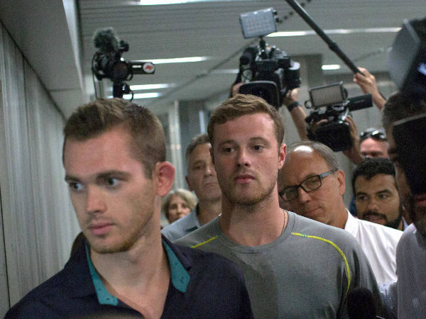 Journalists surround American Olympic swimmers Gunnar Bentz, left, and Jack Conger, center, as they leave the police station at Rio International airport early Thursday (August 18) Journalists surround American Olympic swimmers Gunnar Bentz, left, and Jack Conger, center, as they leave the police station at Rio International airport early Thursday (August 18)