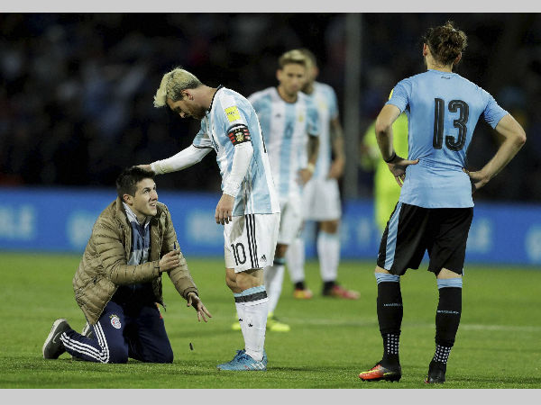 A fan who invaded the pitch kneels in front of Argentina's Lionel Messi, centre, as Uruguay's Gaston Silva looks on during a 2018 World Cup qualifying match in Mendoza, Argentina, on Thursday (September 1). A fan who invaded the pitch kneels in front of Argentina's Lionel Messi, centre, as Uruguay's Gaston Silva looks on during a 2018 World Cup qualifying match in Mendoza, Argentina, on Thursday (September 1).
