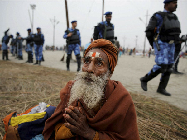 An elderly devotee prays as RAF soldiers patrol at Sangam An elderly devotee prays as RAF soldiers patrol at Sangam