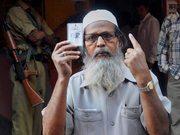 A Muslim voter shows his voter ID card