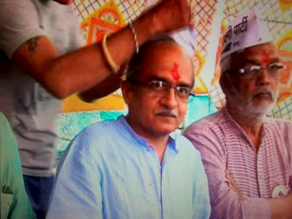 A man removes cap of AAP leader Prashant Bhushan during a press conference