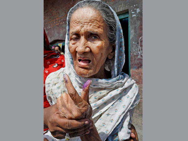 An elderly woman shows her inked finger
