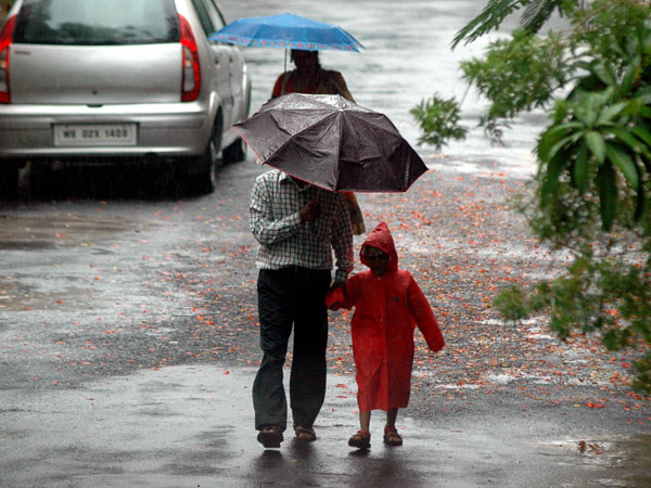 People use umbrellas to shield themselves from rains in Kolkata