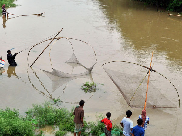 People use Chinese nets as they fish in a river of Agartala