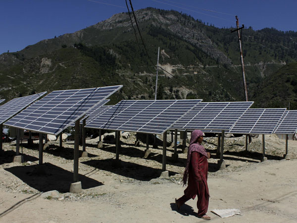 A woman walks past defunct solar panels installed