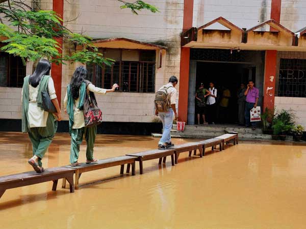 Students using benches to enter their school inundated