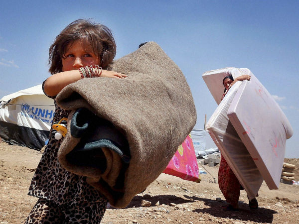 Iraqis who have fled fighting between security forces and al-Qaida inspired militants in their hometown of Tal Afar carry their belongings at Germawa camp for displaced Iraqis, in a hot dusty plain in the largely-autonomous Kurdish area of Dahuk, 260 miles (430 kilometers) northwest of Baghdad Tuesday, June 17, 2014. (AP/PTI photo)