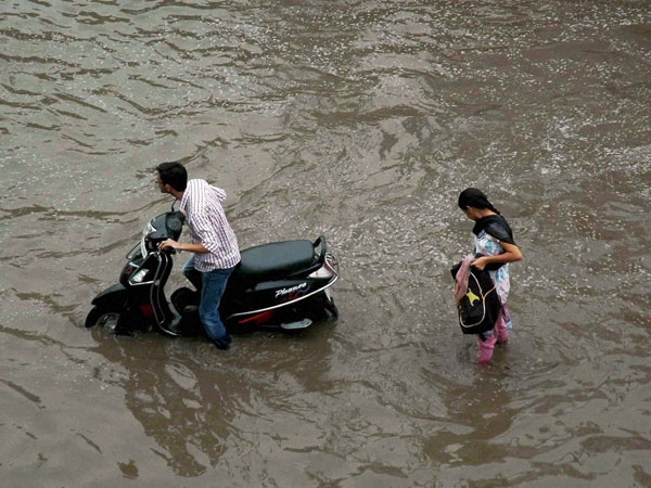 A scooterist wades through a waterlogged street A scooterist wades through a waterlogged street