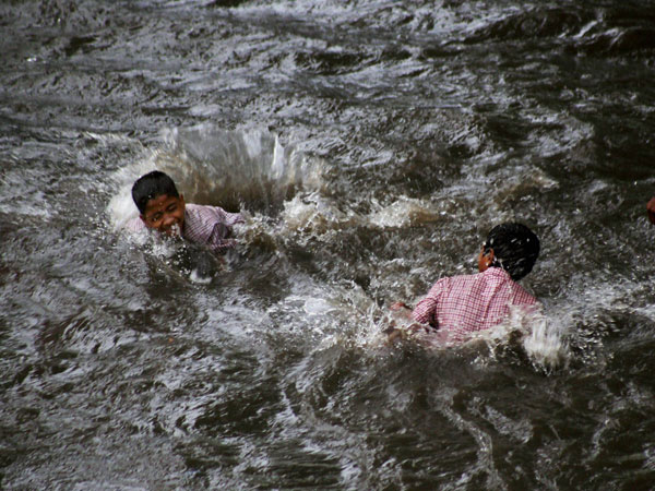 Children playing at a waterlogged road after heavy rains