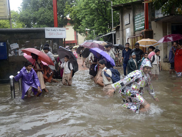 School students play on a waterlogged streets of Mumbai