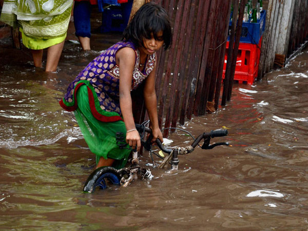 A girl trying to pull her bicycle from a waterlogged road