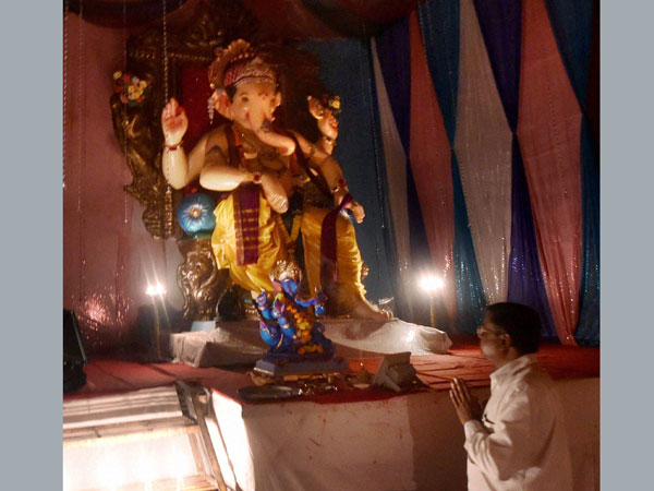 A devotee prays in front of an idol of Ganesh