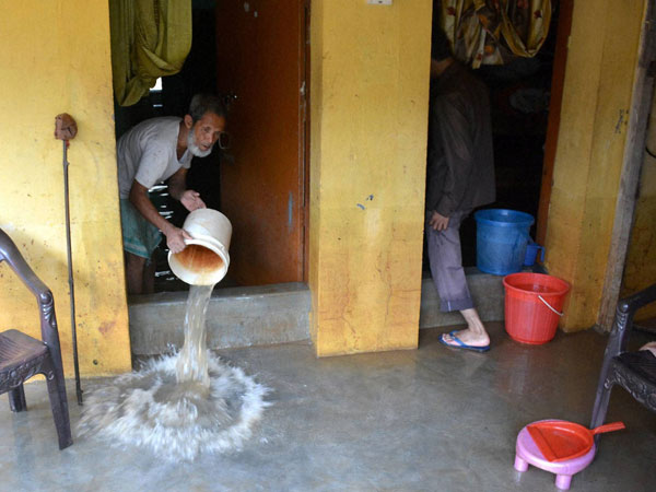 A man washes the floor of his house as the flood water