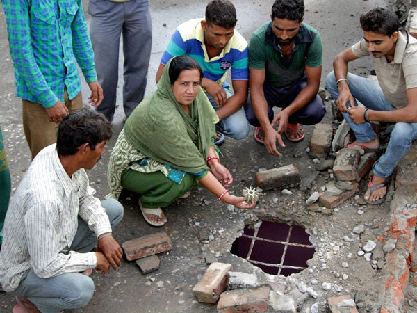 An woman displays the mortar shell fired