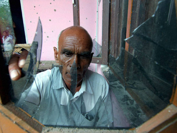 A man shows the broken glass pane of his house