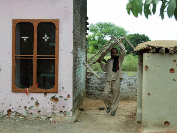 A man walks between the damaged walls of the houses