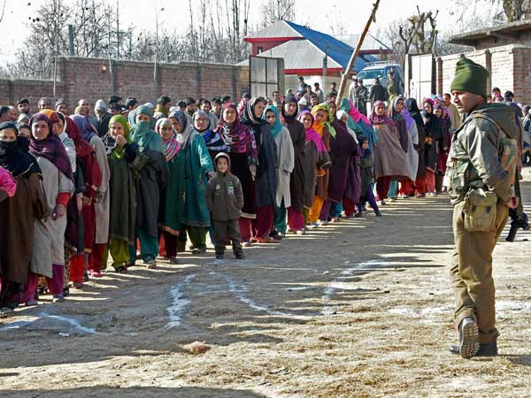 A security jawan stands guard as voters
