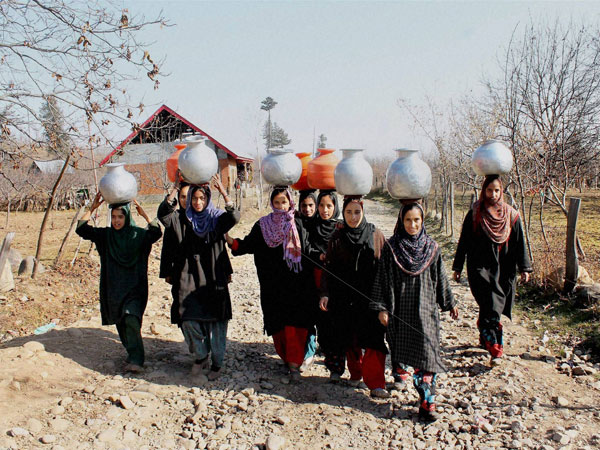 Kashmiri girls carry vessels with drinking water