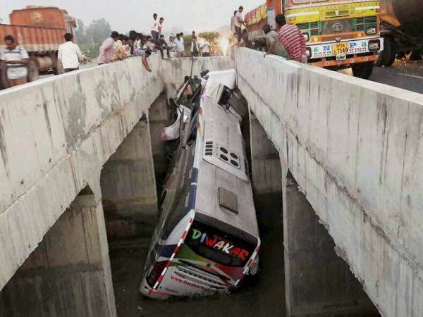 People looking at a private bus after it fell off a bridge into a canal in Vijayawada People looking at a private bus after it fell off a bridge into a canal in Vijayawada