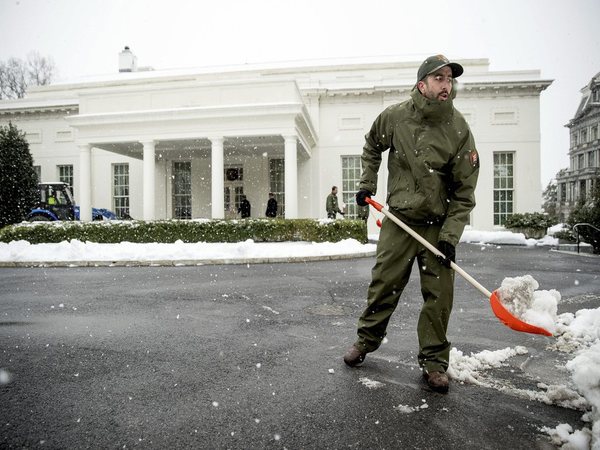 Workers clear snow outside the West Wing of the White House