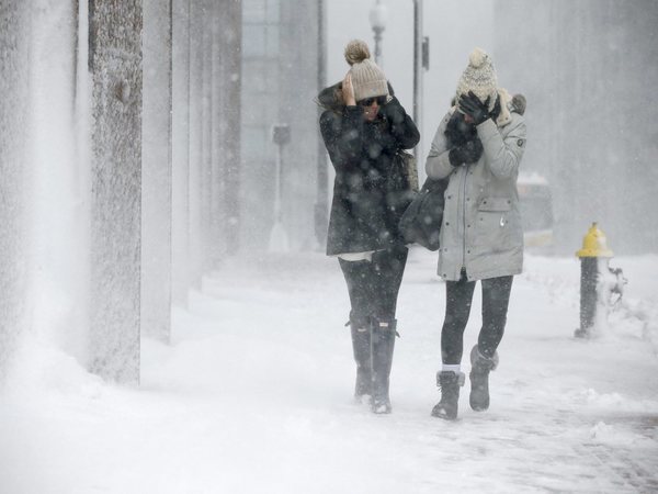 Two women struggle to walk in the blowing snow in Boston