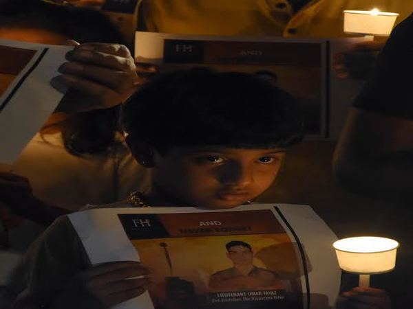 A girl is seen holding the poster and a candle A girl is seen holding the poster and a candle