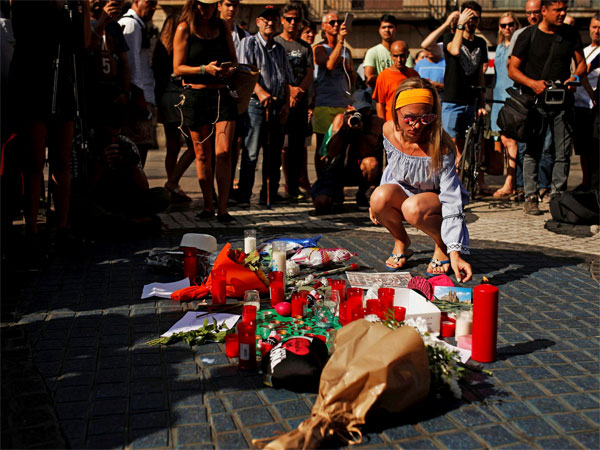 A woman places a postcard of the Barcelona's Sacred Family cathedral next to bunches of flowers in Las Ramblas, Barcelona, Spain, Friday, Aug. 18, 2017. Police on Friday shot and killed five people carrying bomb belts who were connected to the Barcelona van attack, as the manhunt intensified for the perpetrators of Europe's latest rampage claimed by the Islamic State group. PTI photo A woman places a postcard of the Barcelona's Sacred Family cathedral next to bunches of flowers in Las Ramblas, Barcelona, Spain, Friday, Aug. 18, 2017. Police on Friday shot and killed five people carrying bomb belts who were connected to the Barcelona van attack, as the manhunt intensified for the perpetrators of Europe's latest rampage claimed by the Islamic State group. PTI photo