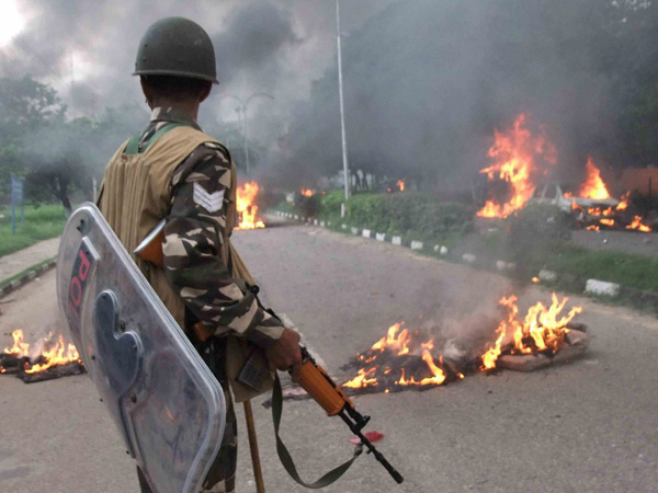 A Security personnel stands towards vehicles burning in violence following Dera Sacha Sauda chief Gurmeet Ram Rahim’s conviction in Panchkula on Friday. PTI Photo A Security personnel stands towards vehicles burning in violence following Dera Sacha Sauda chief Gurmeet Ram Rahim’s conviction in Panchkula on Friday. PTI Photo