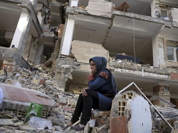 An earthquake survivor sits on debris