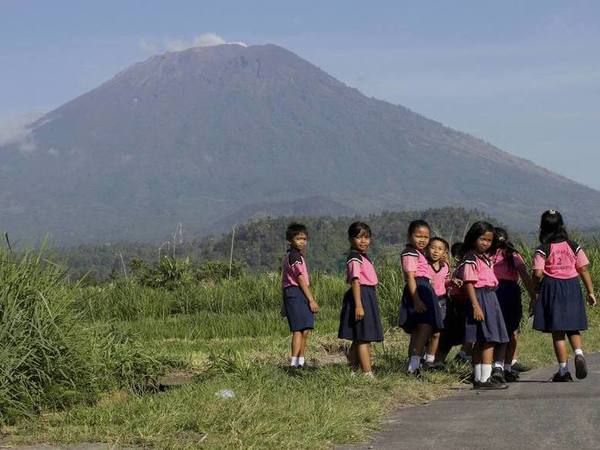 Schoolchildren walk with Mount Agung volcano Schoolchildren walk with Mount Agung volcano