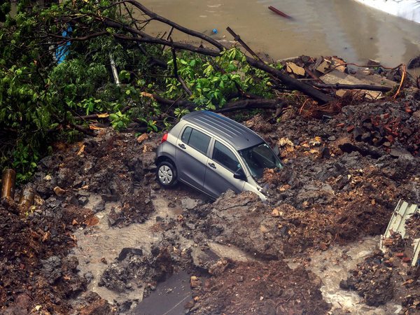 A car struck in debris after a wall collapsed at a construction site in Antop Hill, Wadala East area, in Mumbai