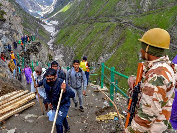 Security personnel look on as a batch of pilgrims are on their way towards the holy cave shrine of Amarnath