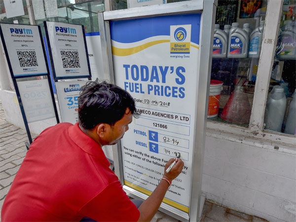 A worker writes the updated fuel prices on a board at a filling station A worker writes the updated fuel prices on a board at a filling station